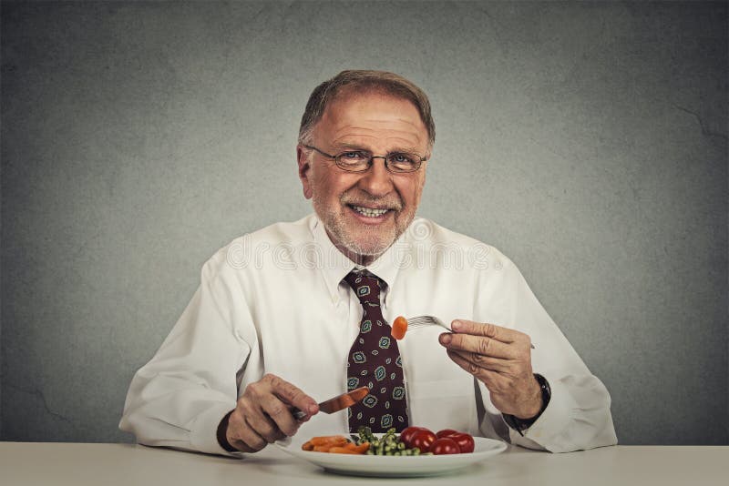 Happy senior man eating fresh vegetable salad