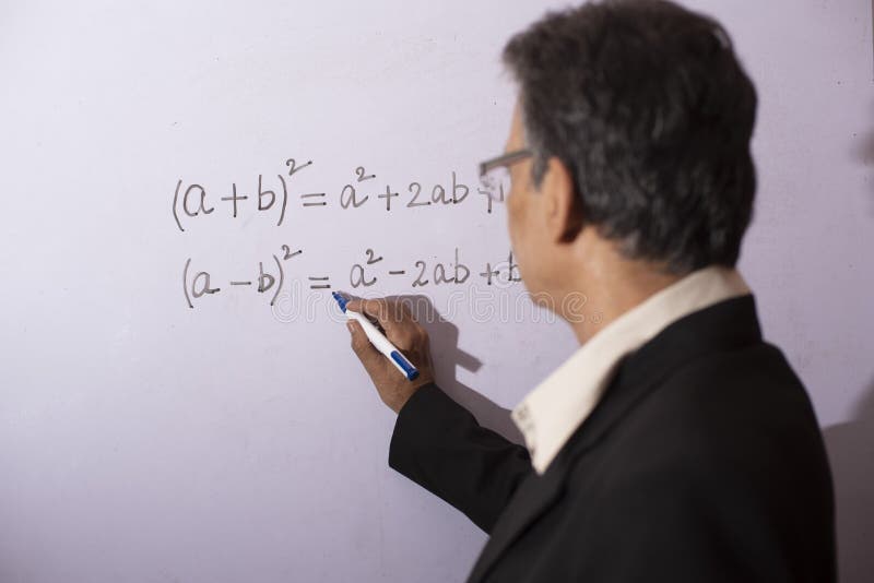 An senior man with formal suit and glasses writing on white board while taking online classes during lock down period.