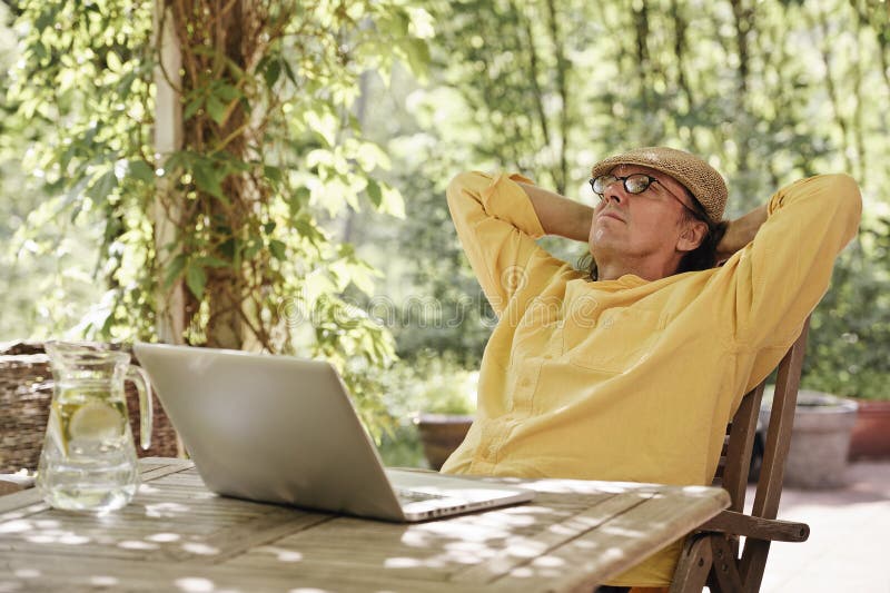 Senior man in the garden with a laptop royalty free stock images