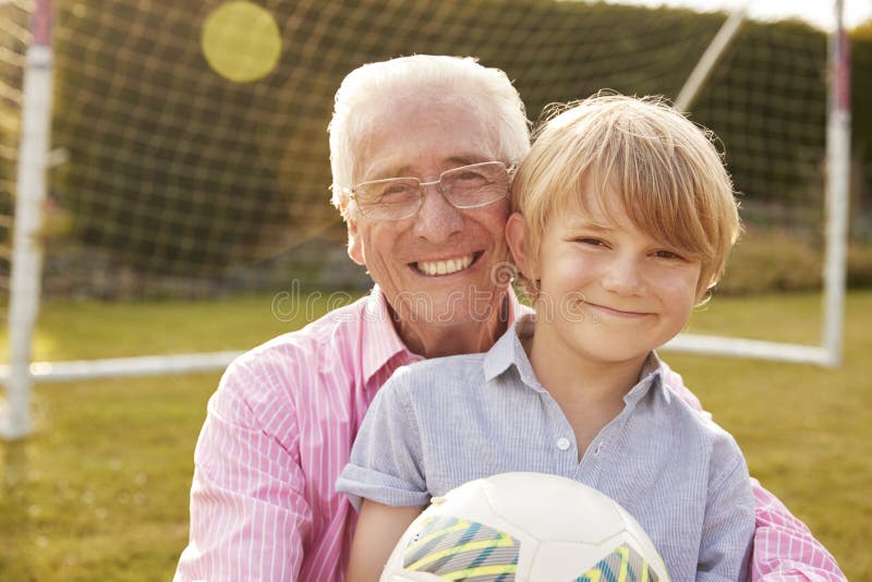 Senior men and grandson holding ball smiling at camera