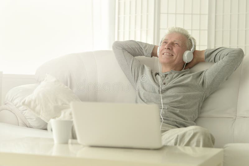 Senior man in headphones with laptop