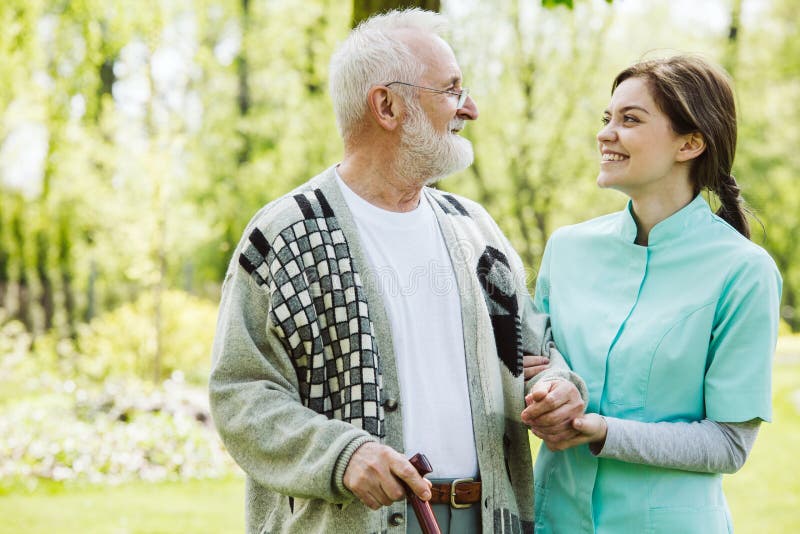 Senior man with volunteer in the garden of professional care home stock photo