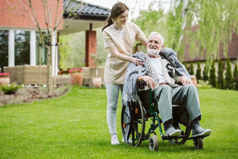 Senior with helpful volunteer in the garden of professional care home stock photo