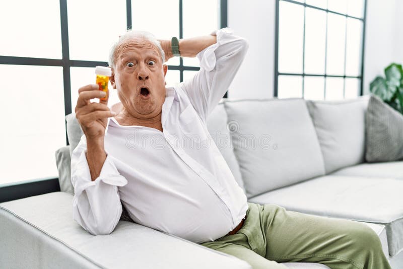 Senior Man Holding Pills Crazy and Scared with Hands on Head, Afraid