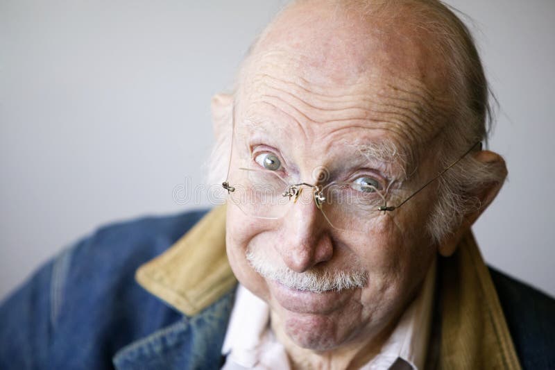 Ritratto di un anziano che indossa occhiali e un giubbotto di jeans in studio.