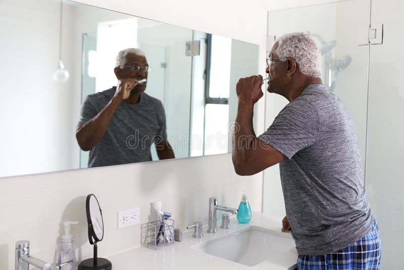 Senior Man Looking At Reflection In Bathroom Mirror Wearing Pajamas Brushing Teeth stock images Senior Man Looking At Reflection In Bathroom Mirror Wearing Pajamas Brushing Teeth stock images