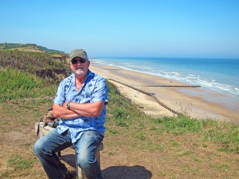 Senior man relaxing on a bench by the ocean.