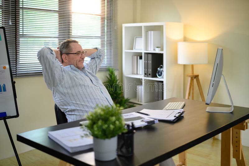 Senior man relaxing after completing tasks in a modern workspace royalty free stock images