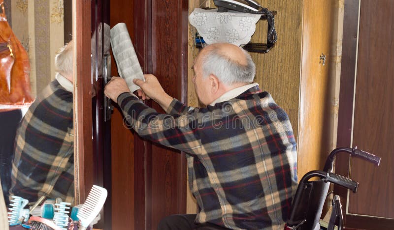 Senior man retrieving a newspaper through a door