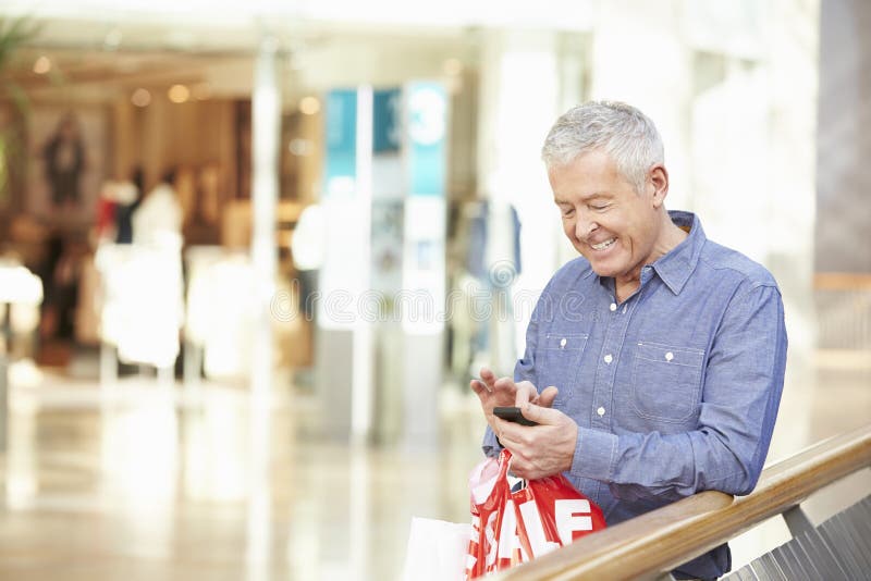 Senior Man In Shopping Mall Using Mobile Phone