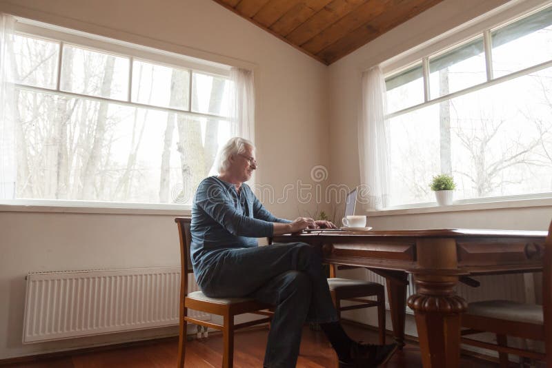 Senior man sitting at desk working on computer