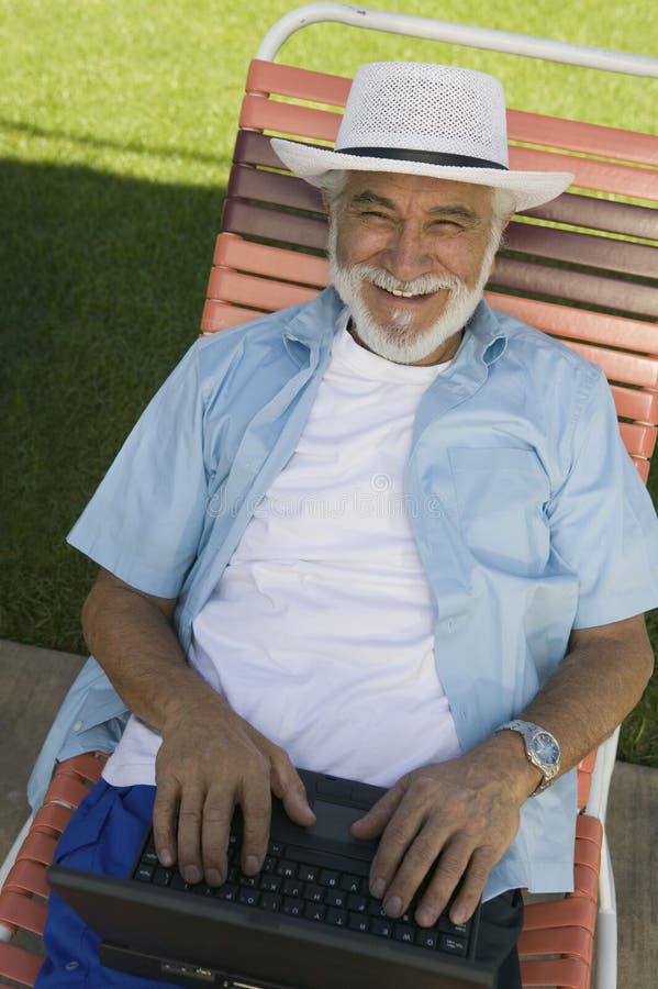 Senior Man sitting on Lawn Chair Using Laptop elevated view portrait. royalty free stock image