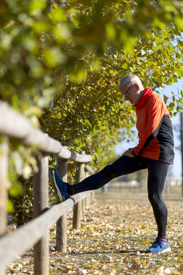 Senior man stretching his leg. Doing workout in nature. Healthy living. Forest. Outdoors stock image Senior man stretching his leg. Doing workout in nature. Healthy living. Forest. Outdoors stock image