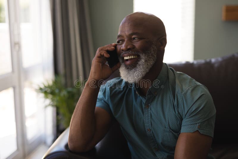 Senior man talking on mobile phone in living room