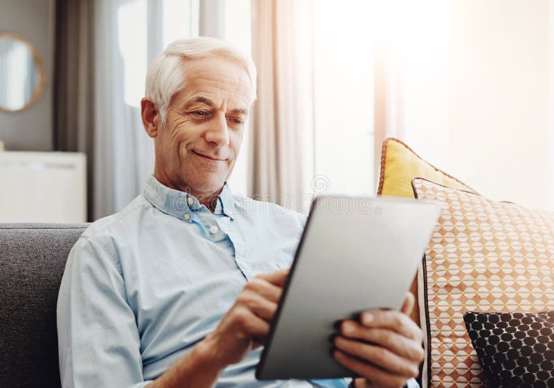 Senior man, technology and relax on sofa in home for typing email, communication and reading online news. Elderly person royalty free stock photo