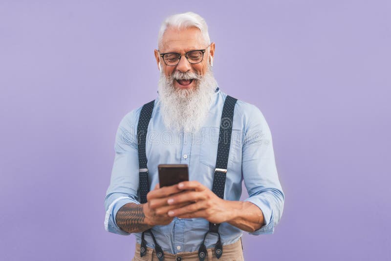 Senior man using mobile smartphone and listening music with airpods - Happy mature male having fun with new trends technology