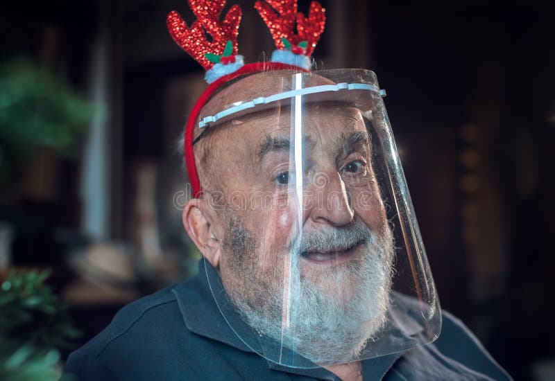 Senior Man Wearing a Protective Visor and Reindeer Ears Stock Photo