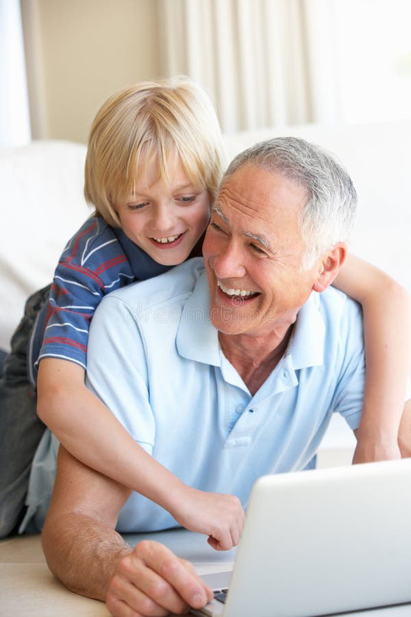 Senior man with young boy using laptop computer smiling. Laptop personal computer stock images, royalty-free photos and pictures