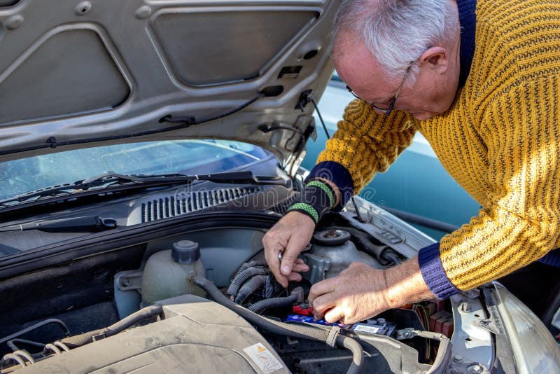 Senior Mechanic Worker Checking and Changing a Car Battery. Stock Photo