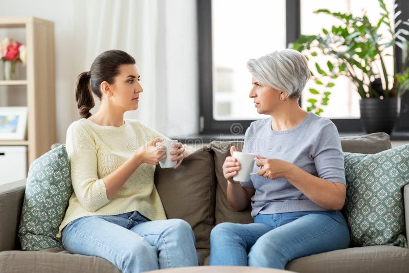 Senior mother and adult daughter drinking coffee