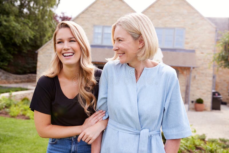 Senior Mother And Adult Daughter Walking And Talking In Garden Together stock photo Senior Mother And Adult Daughter Walking And Talking In Garden Together stock photo