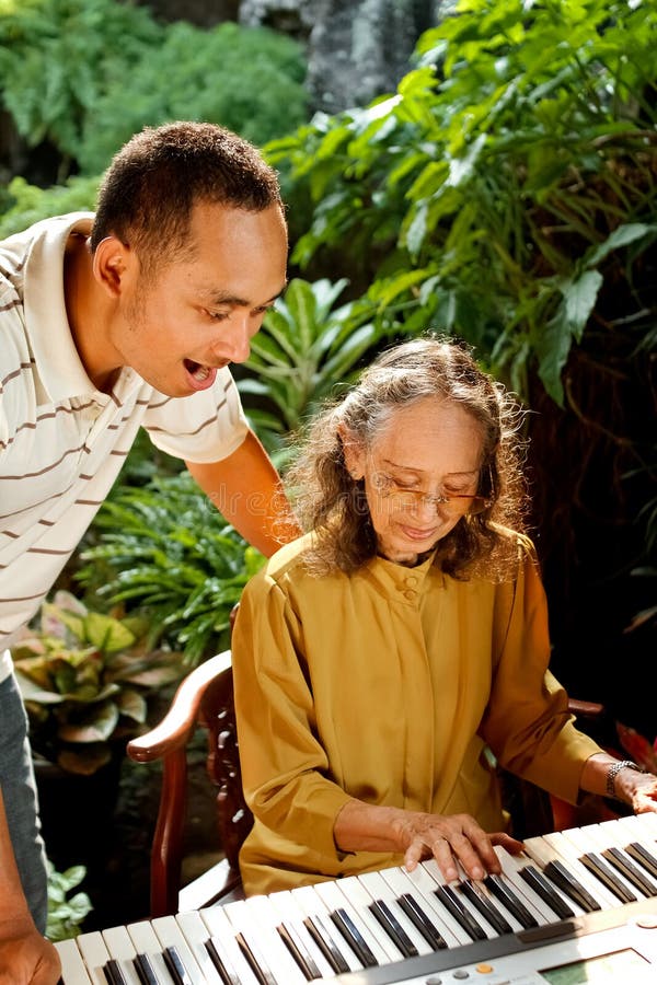 Asian ethnic family portrait of elderly women play piano together with young adult man. Asian ethnic family portrait of elderly women play piano together with young adult man