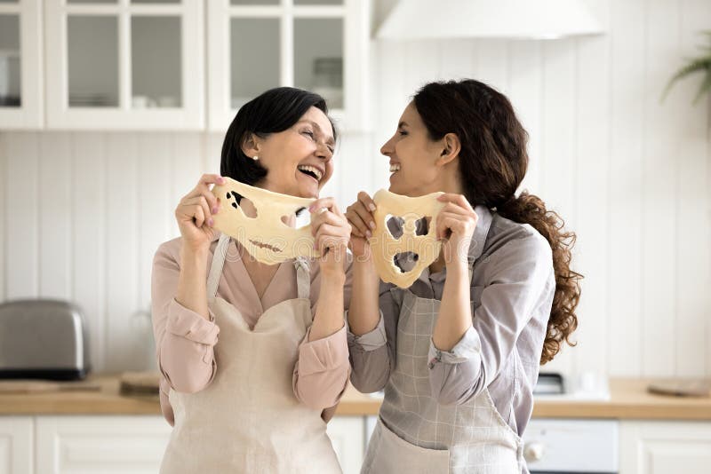 Senior Mutter junge Tochter schneiden lustige Gesichter in flacher Teig lizenzfreies stockbild