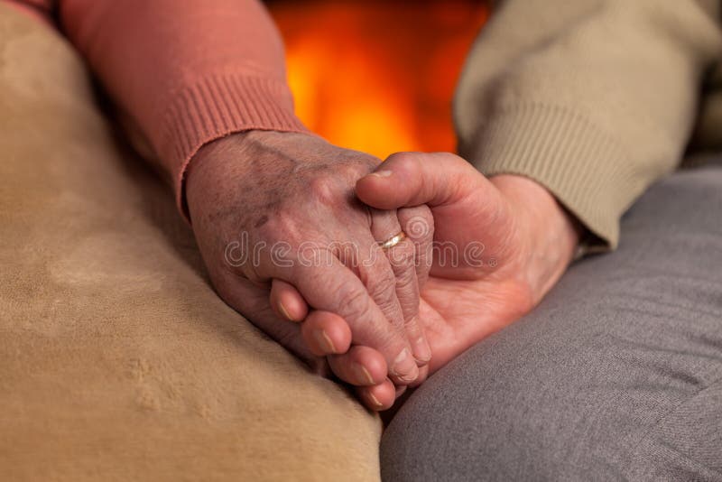 Senior old hands holding in front of fireplace royalty free stock photo