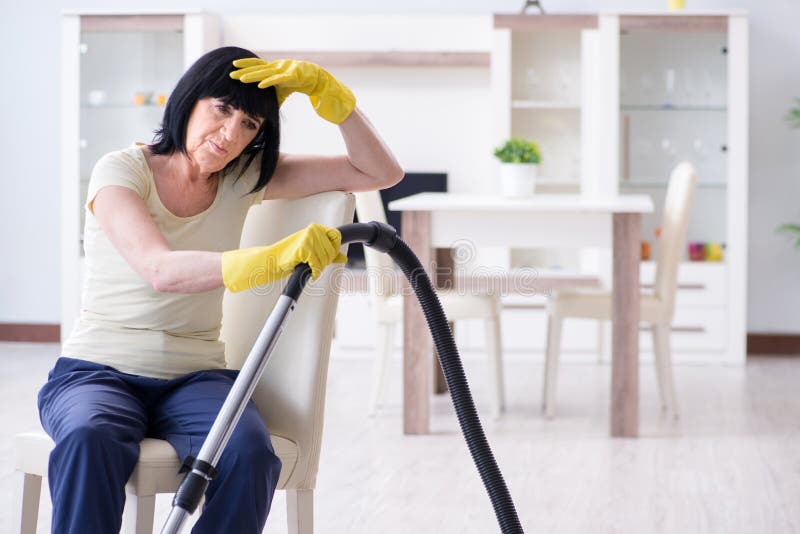 The senior old woman tired after vacuum cleaning house royalty free stock images The senior old woman tired after vacuum cleaning house royalty free stock images