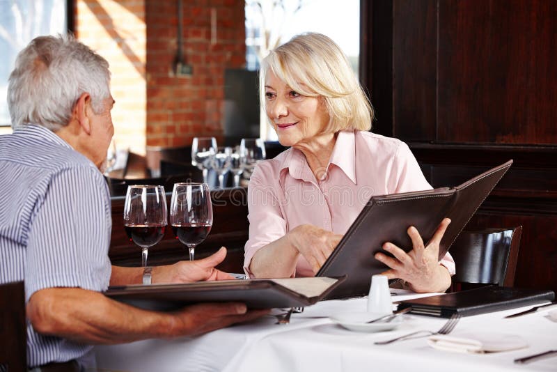 Two senior people with menu in restaurant for lunch