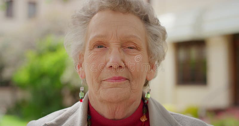 Senior portrait, smile and face on an elderly woman standing outside feeling happy and content in retirement outside old