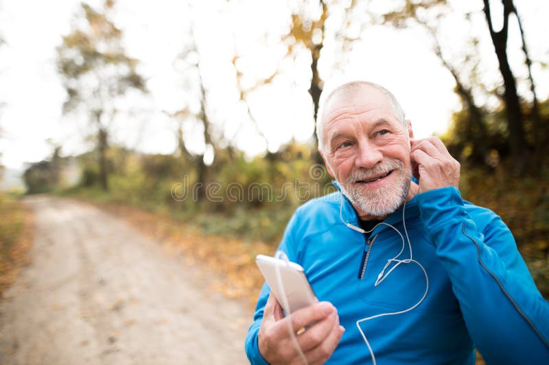 Senior runner in nature with smart phone with earphones.