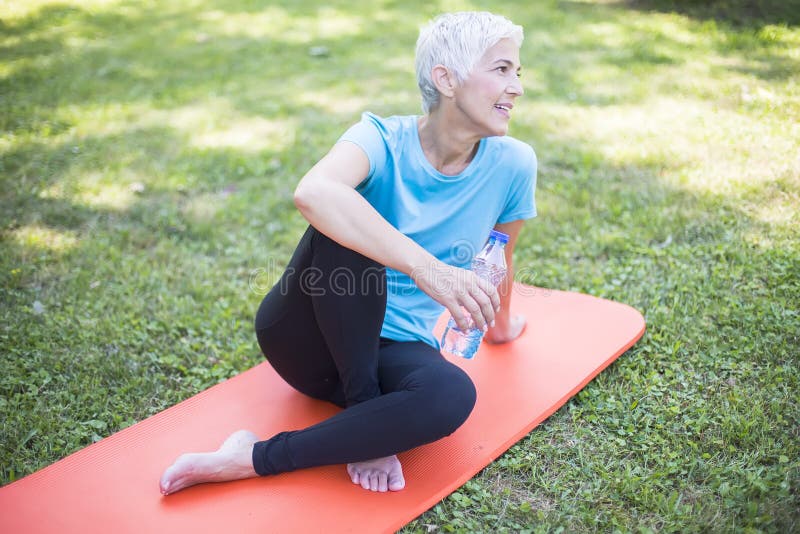 Senior Sportive Woman Sitting on Mat Outside and Resting after Workout ...