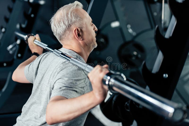 senior sportsman training with barbell in sport center