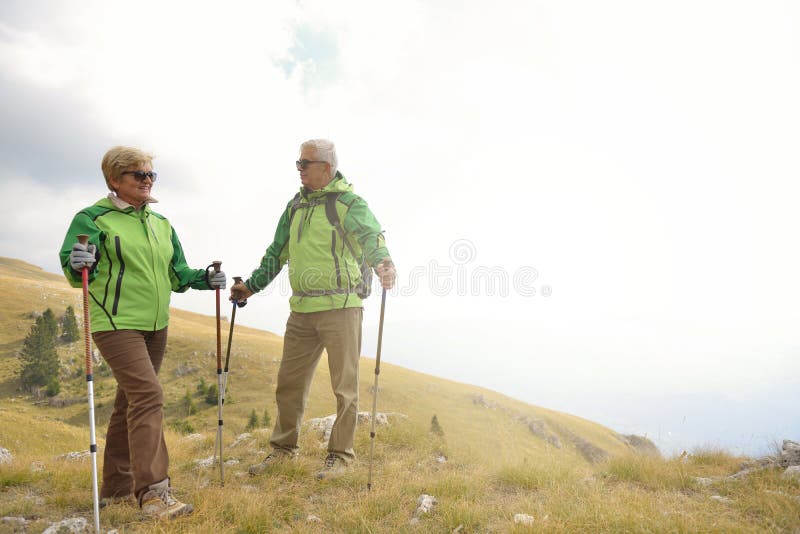 Senior tourist couple hiking at the beautiful mountains