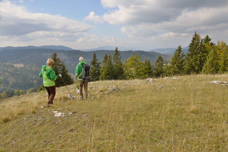 Senior tourist couple hiking at the beautiful mountains