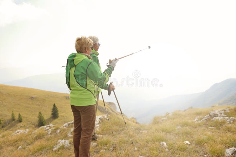 Senior tourist couple hiking at the beautiful mountains