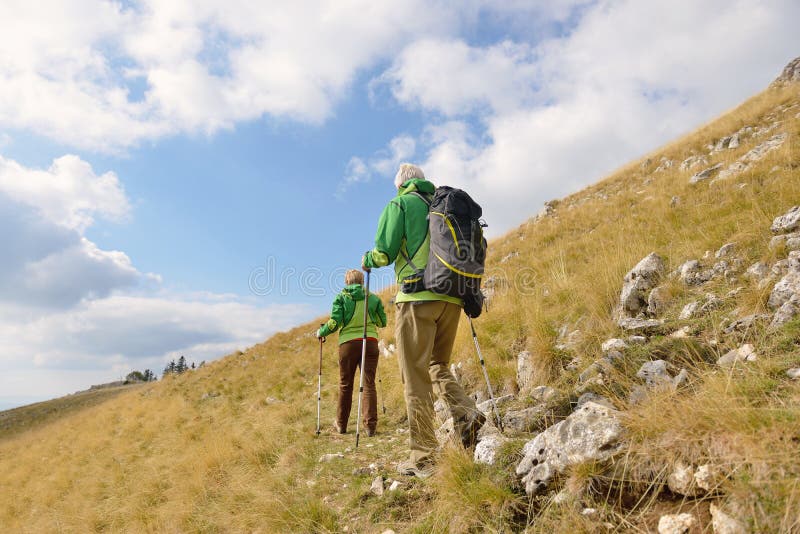 Senior tourist couple hiking at the beautiful mountains