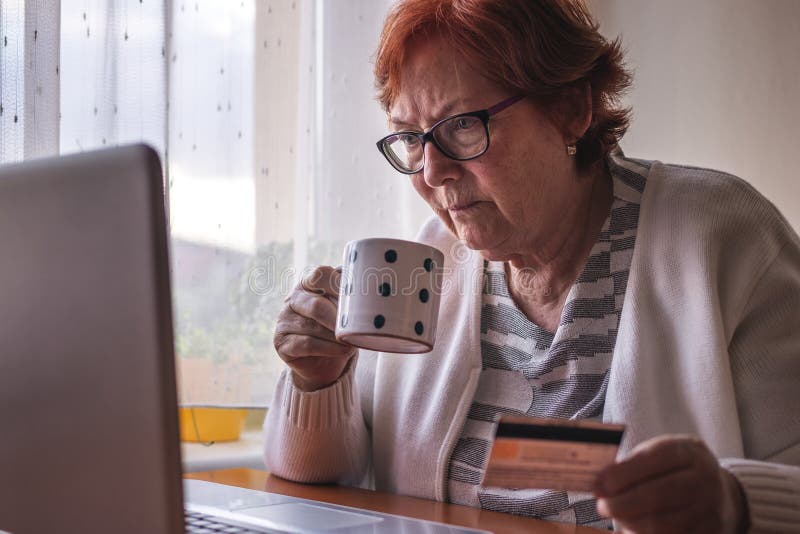 Senior woman using laptop and online shopping by credit card from home. Old people and internet. Senior woman using laptop and online shopping by credit card from home. Old people and internet