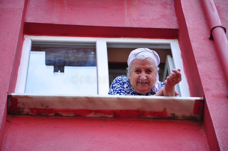 A senior woman loking out from window