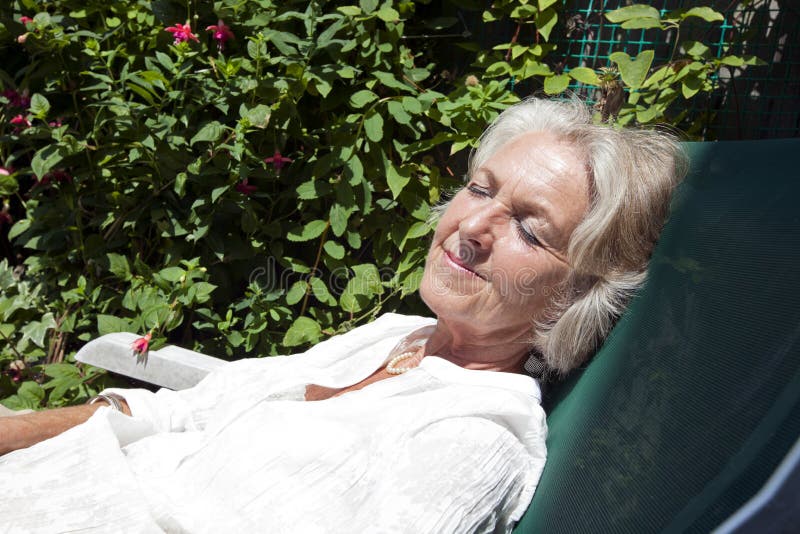 Senior woman with eyes closed relaxing on lounge chair in garden