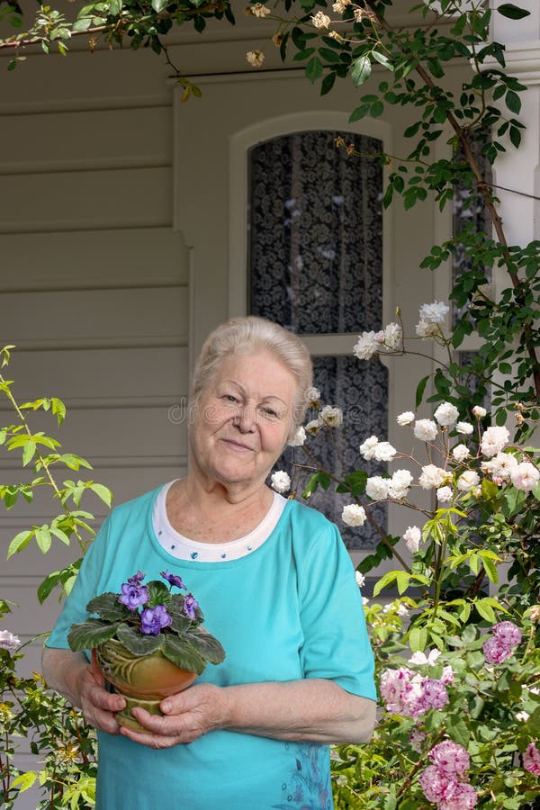 Senior woman with flower in pot in her garden