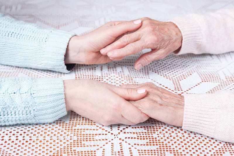 Senior woman with her caregiver at home. Holding hands, horizontally top view closeup. royalty free stock photography Senior woman with her caregiver at home. Holding hands, horizontally top view closeup. royalty free stock photography