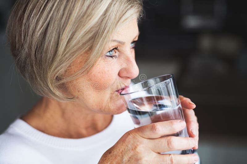 Senior woman drinking water in the kitchen. stock photos Senior woman drinking water in the kitchen. stock photos