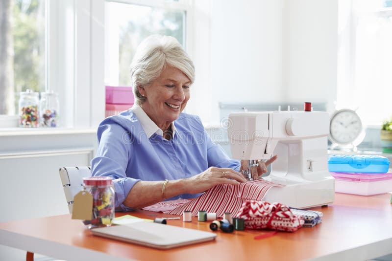 Senior Woman Making Clothes Using Sewing Machine at Home Stock Image