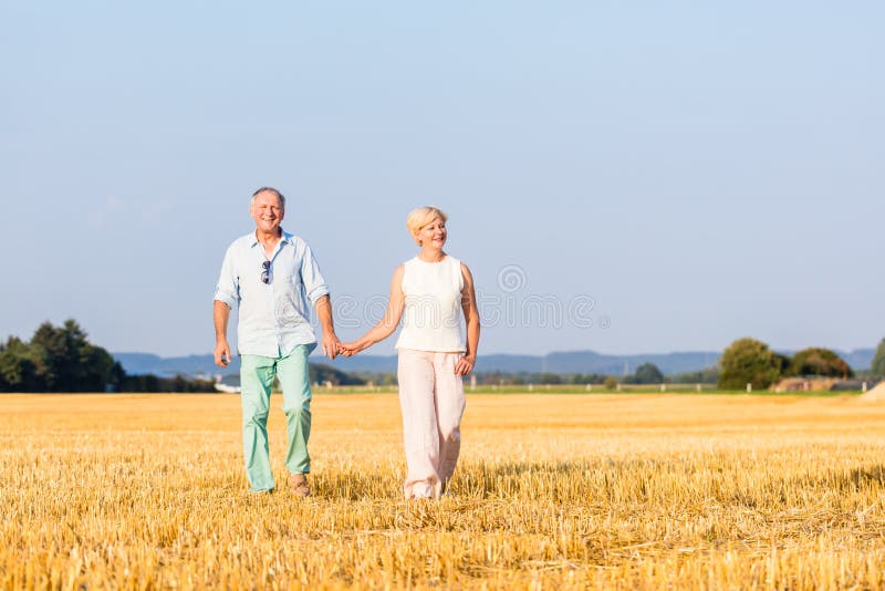 Senior woman and man holding hands having walk