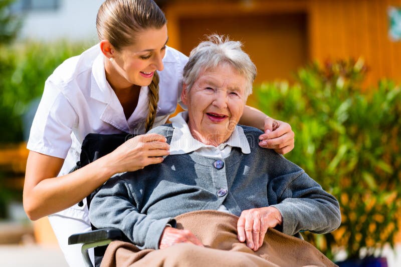 Senior women in nursing home with nurse in garden sitting in wheelchair. Senior women in nursing home with nurse in garden sitting in wheelchair