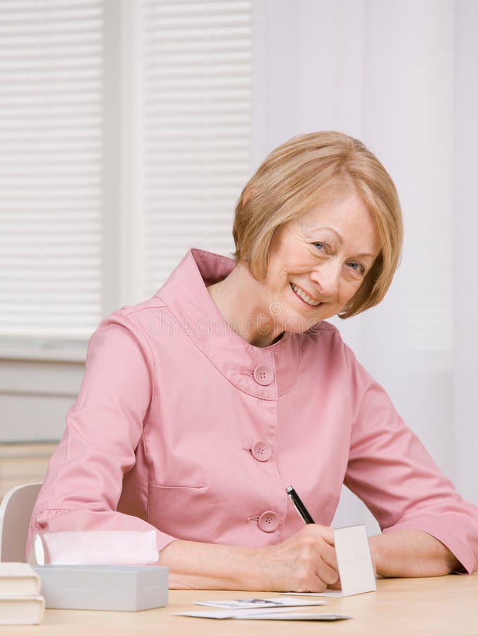 Senior woman paying bills at desk stock photos
