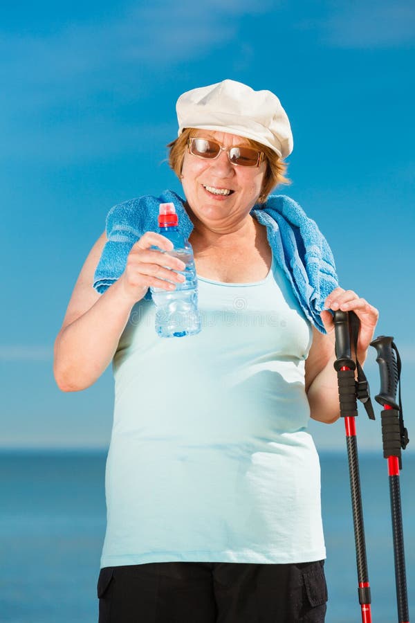 Senior woman practicing nordic walking on beach stock photo Senior woman practicing nordic walking on beach stock photo