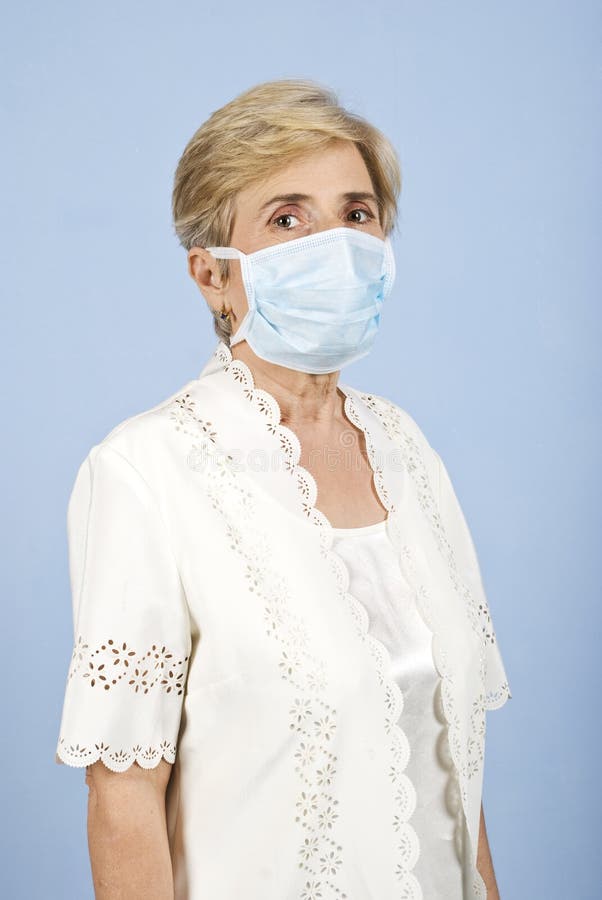 Portrait of senior woman with protective mask standing in profile and looking you on blue background, check also. Side profile mask stock images, royalty-free photos and pictures